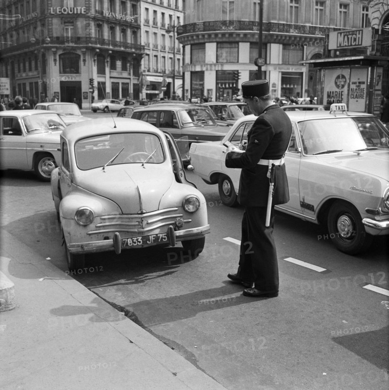 Pariser Bilder [The street life of Paris] Description: Agent writes a ticket from Date: 1965 Location: France, Paris Keywords: cars, fines, street images, traffic police