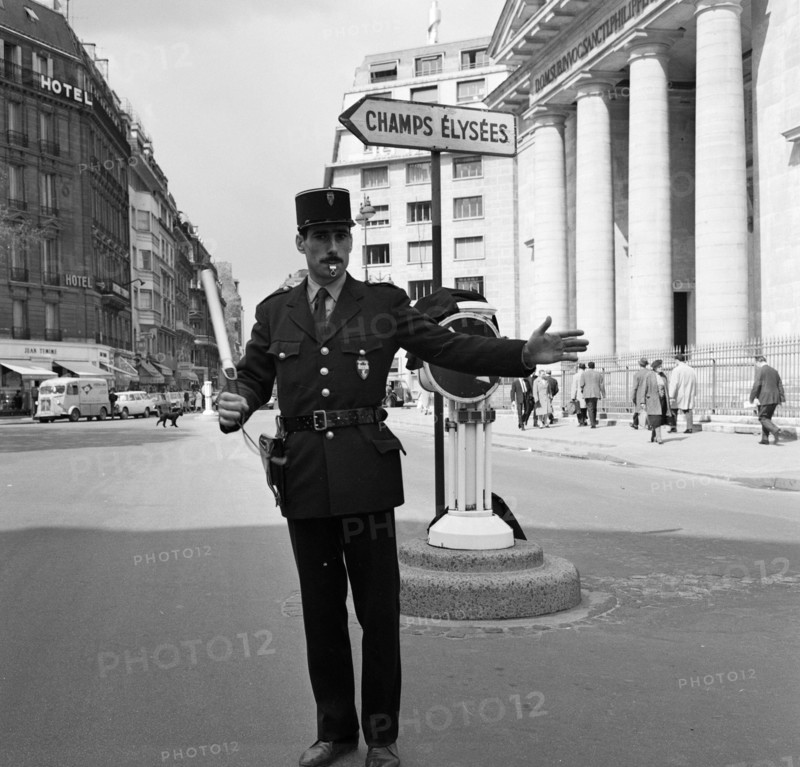 Pariser Bilder [The street life of Paris] Description: Agent regulates traffic in the Rue du Faubourg-Saint-Honoré in front of the church of St. Philippe du Roule near the Champs Elysees Date: 1965 Location: Champs Elysées, France, Paris Keywords: church buildings, street statues, traffic police, columns