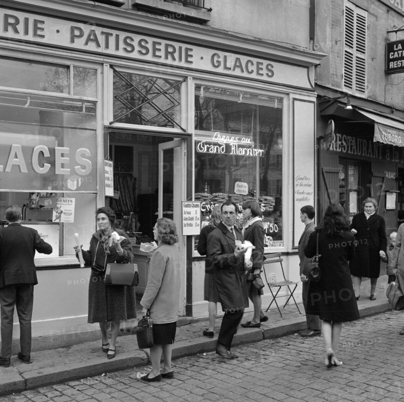 Pariser Bilder [Paris Street Life]  Customers on the sidewalk in front of a pastry shop Date: 1965 Location: France, Paris Keywords: confectioners, pastries, street statues, shops