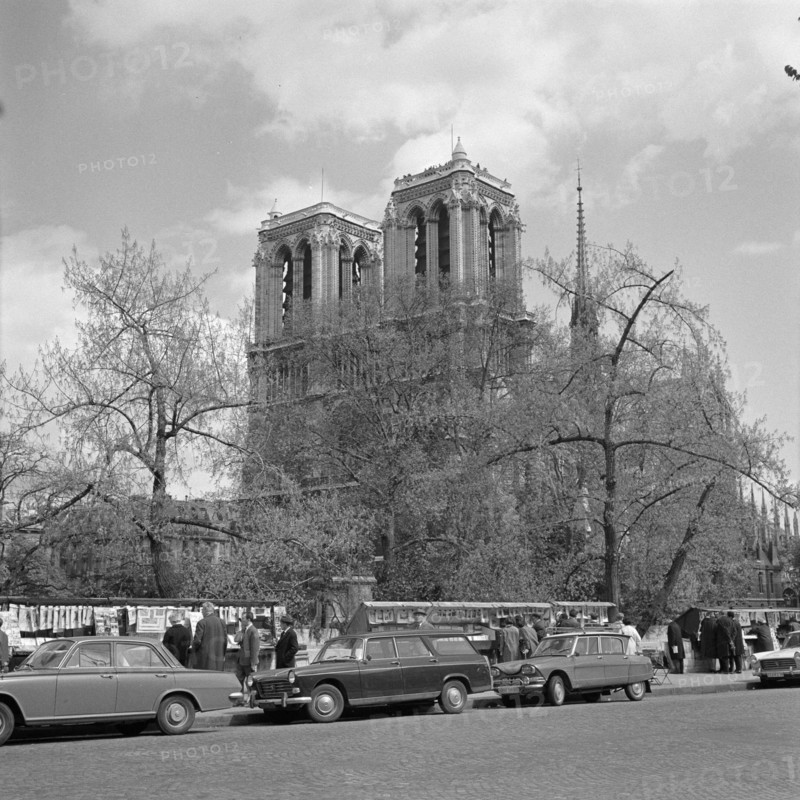 Pariser Bilder [The street life of Paris]  Cathedral Notre-Dame, with in the foreground the stalls on the quays of the Seine Annotation: The booksellers with a stall along the Seine are bouquinistes. They sell old books and prints from large chests attached to the parapet Date: 1965 Location: France, Paris Keywords: cars, cathedrals, street sculptures Institution name: Notre Dame