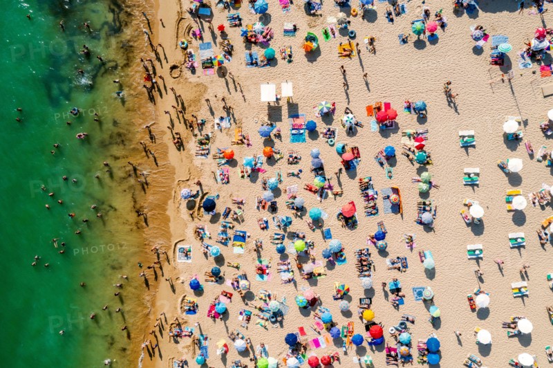 Drone shot of many people enjoying the beach and the ocean - vacation pattern. Rocha Beach in Portimao, Portugal