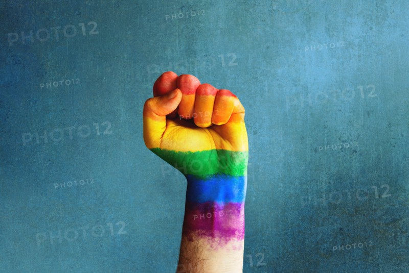 Raised rainbow fist of a man for PRIDE month and the LGBTQIA+ movement. Pride day for sexuality freedom, love diversity celebration and the fight for