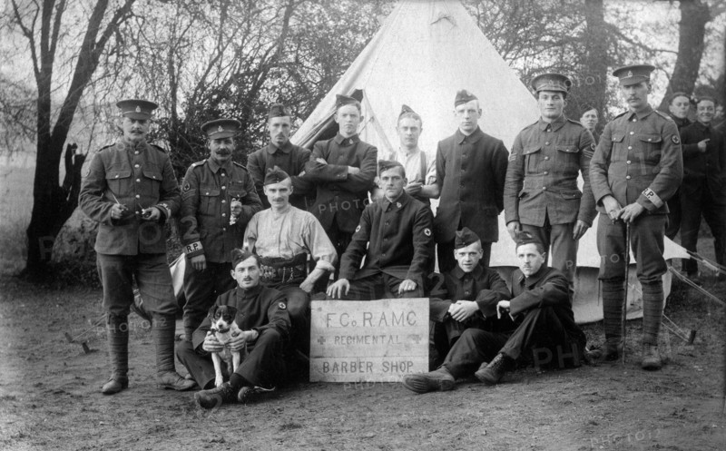 Aldershot, Hampshire. 1914 – British army soldiers of the Regimental Barber Shop, ‘F’ Company, Royal Army Medical Corps at Redan Hill Fort, Aldershot in 1914. The men are posing with their dog mascot in front of a bell tent. Some of the soldiers are wearing standard Khaki with Regimental Police armbands. The rest are wearing temporary blue serge uniforms, known as ‘Kitchener blues’. As a result of the War Office's failure to obtain a sufficient quantity of standard khaki uniforms in the opening weeks of the First World War, this alternative was introduced as an emergency measure.
