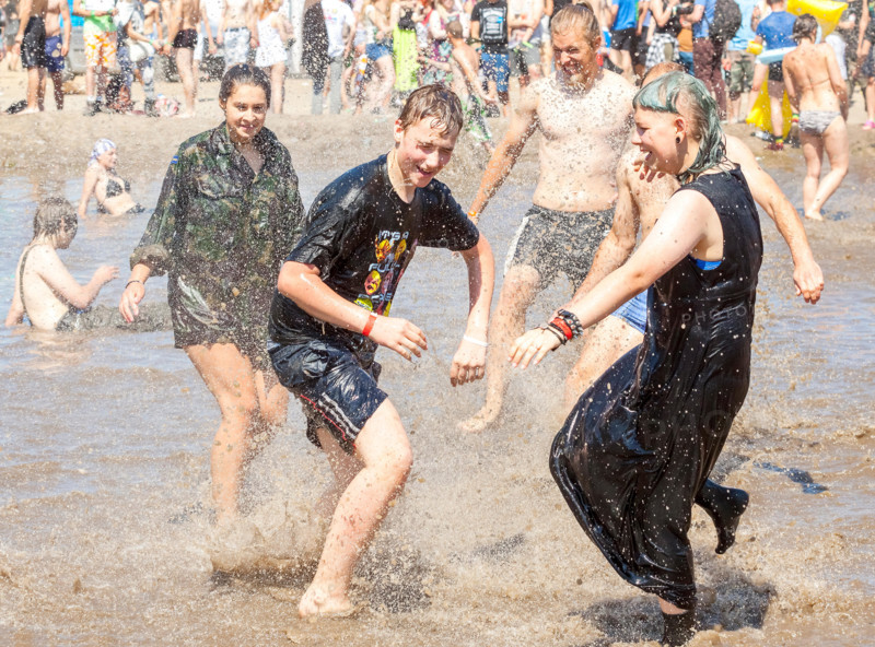 Young people playing in mud pool during 21th Woodstock Festival Poland