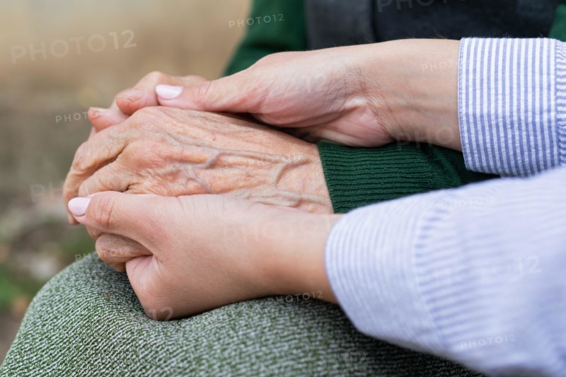 Close up picture of caregiver holding senior woman's wrinkled hands