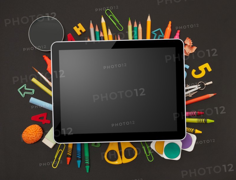 Digital tablet and school supplies on blackboard