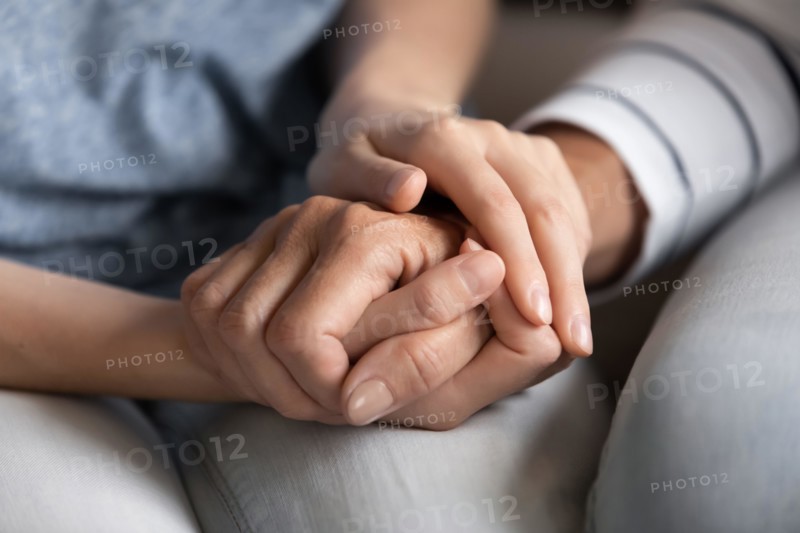 Millennial woman holding hand of elder female friend helping supporting