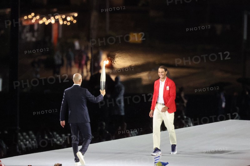 July 26th, 2024 - Paris, France: torchbearer Zinedine Zidane hands the Olympic Flame to Rafael Nadal during the Opening Ceremony of the Paris 2024 Oly