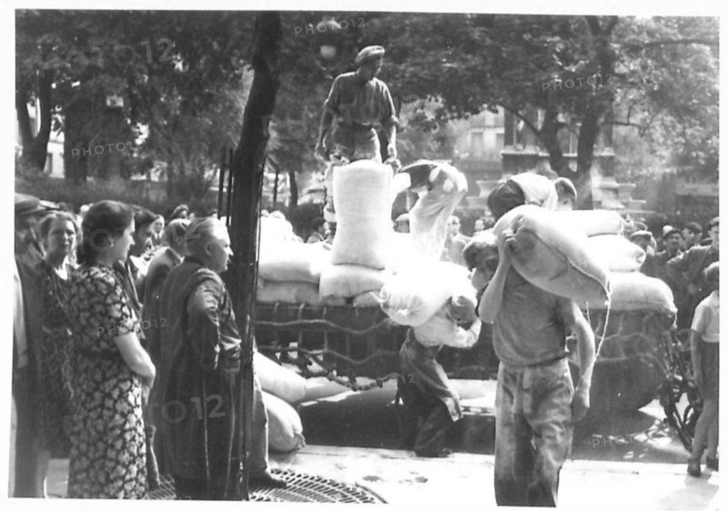 Parisians observe food supplied by the British being unloaded from lorries at the Les Halles market in Paris, British Army, 21st Army Group.
