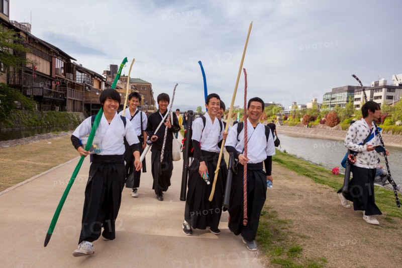 School boys carrying archery equipment, walk along the sides of the Kamo River in Gion, Kyoto, Japan.