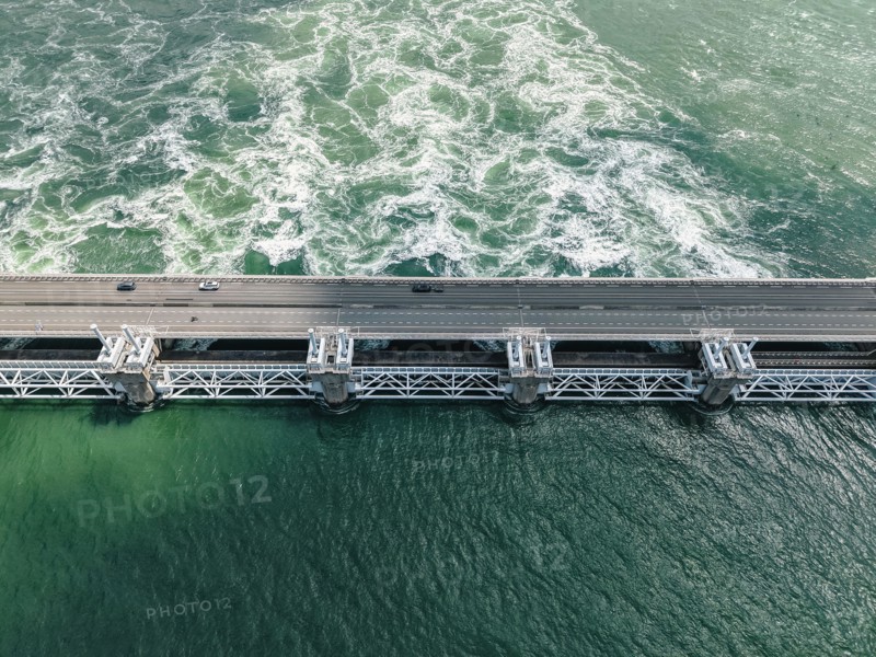 Oosterscheldekering, Delta Works sea barrier from above. Cars driving on the highway, water churning below. Engineering success, safety concept