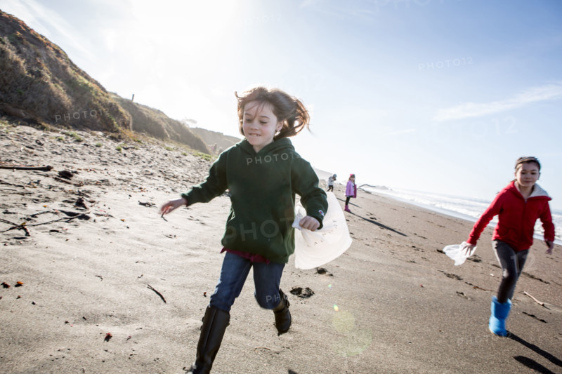 Girls picking up trash on beach cleanup day.