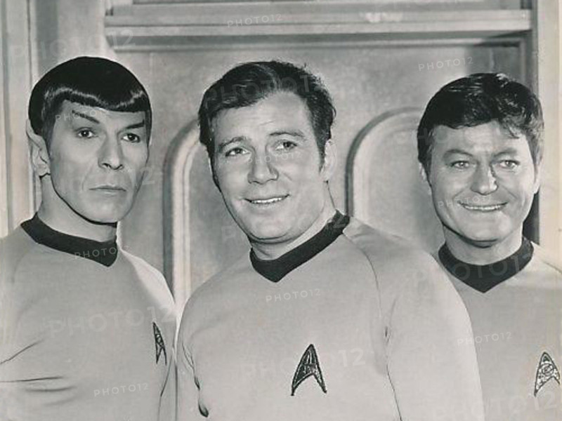 A cropped image from the 1969 'Star Trek' series featuring Leonard Nimoy, William Shatner, and De Forest Kelley as Spock, Captain Kirk, and Dr. McCoy.