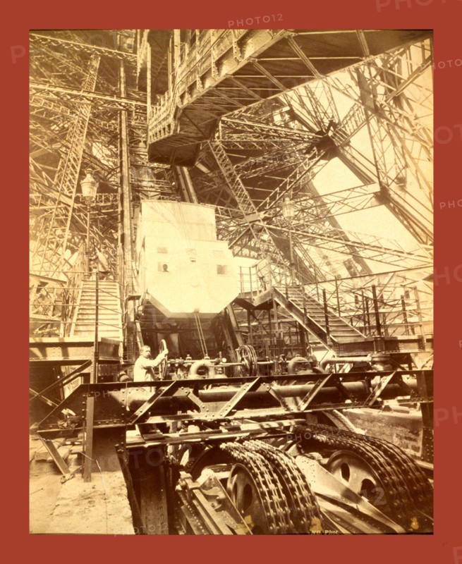 Eiffel Tower machinery with a man beside the wheel that raises elevator, during the Paris Exposition, France, between 1887 and 1889, Napoleon Dufeu