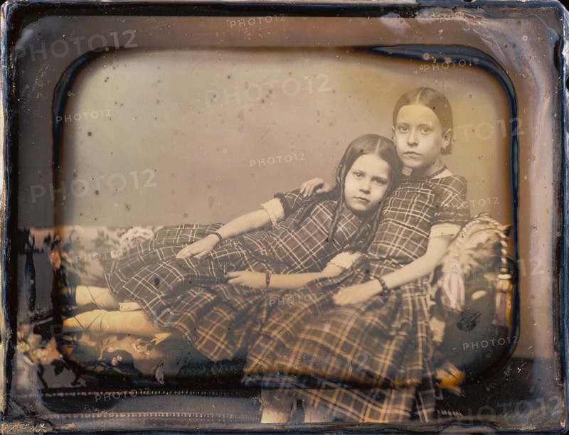 [Portrait of two girls reclining on chaise lounge]