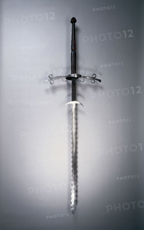 Two-Handed Sword with Flamboyant Blade, 1550-1600. Germany, second half 16th Century. Steel, leather and wood grip with brass rivets; bronze pommel; overall: 168.9 cm (66 1/2 in.); blade: 118.7 cm (46 3/4 in.); quillions: 50.5 cm (19 7/8 in.); grip: 49.2 cm (19 3/8 in.); ricasso: 26.7 cm (10 1/2 in.).
