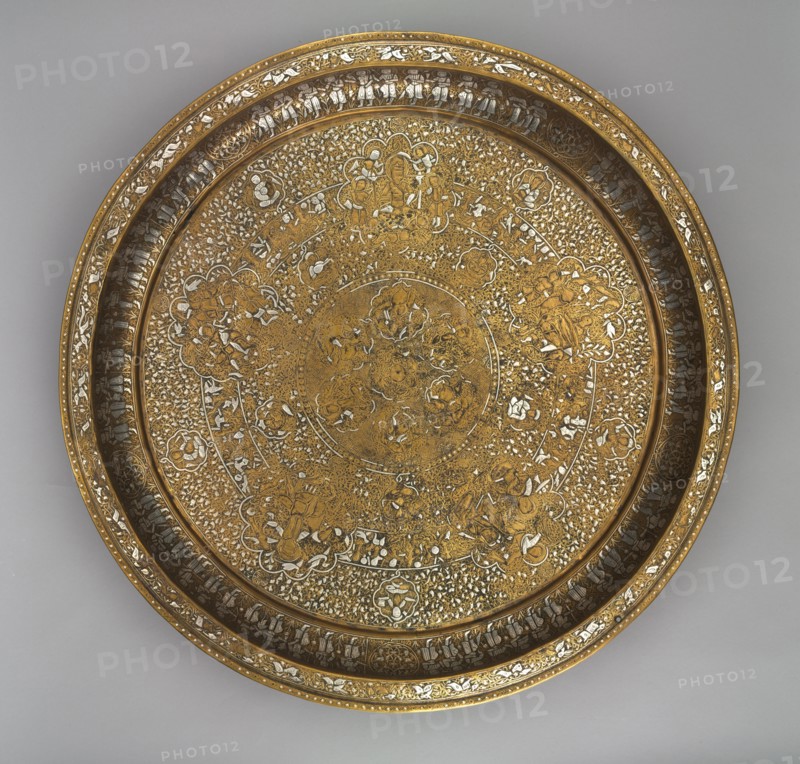 Tray Portraying Courtly Pleasures, 1240s. Syria, Ayyubid Period, 13th century. Sheet brass inlaid with silver; diameter: 53.8 cm (21 3/16 in.); overall: 5.8 cm (2 5/16 in.).
