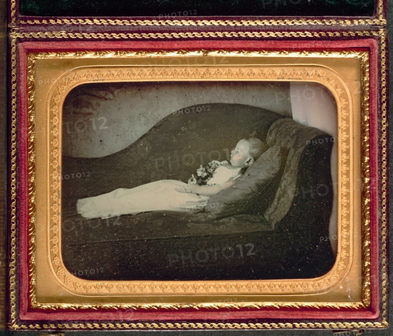 Dead Child On a Sofa, c. 1855. Unidentified Photographer. Daguerreotype, applied color, quarter-plate; image: 6.3 x 8.7 cm (2 1/2 x 3 7/16 in.); case: 11.8 x 9.4 cm (4 5/8 x 3 11/16 in.); mounted: 8.2 x 10.7 cm (3 1/4 x 4 3/16 in.); matted: 50.8 x 61 cm (20 x 24 in.)