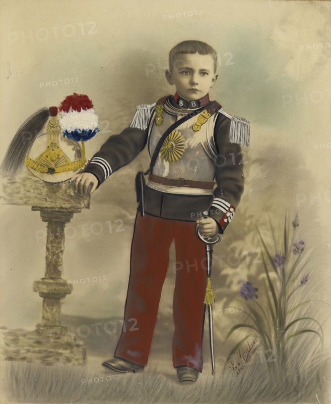 Boy in Military Dress with Helmet on Stand; E. Goubier, French, active 1890s - 1900s, 1899; Hand-colored gelatin silver print