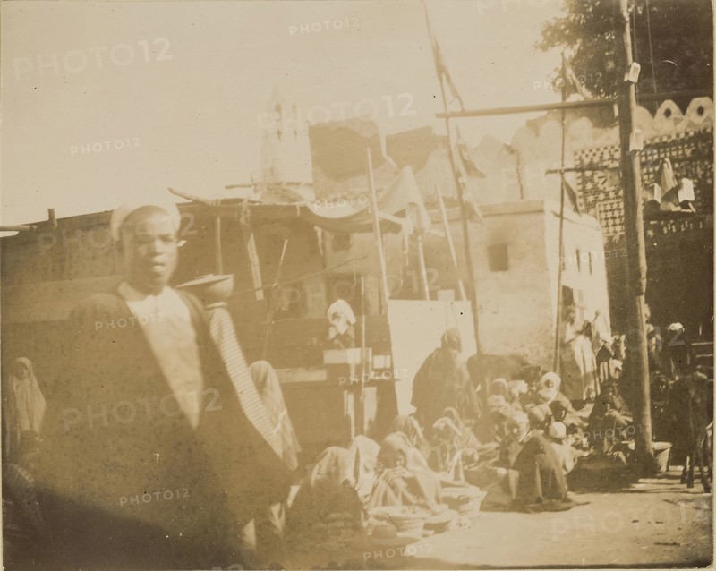 Group of people sitting on ground in a row; about 1860 - 1880; Tinted Albumen silver print