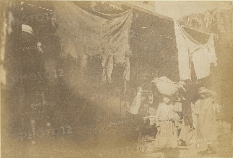 Figures in front of booth; about 1860 - 1880; Tinted Albumen silver print