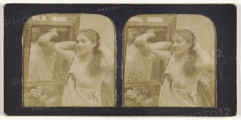 Woman before mirror with hands behind head, one breast exposed; French; 1855 - 1860; Hand-colored Albumen silver print