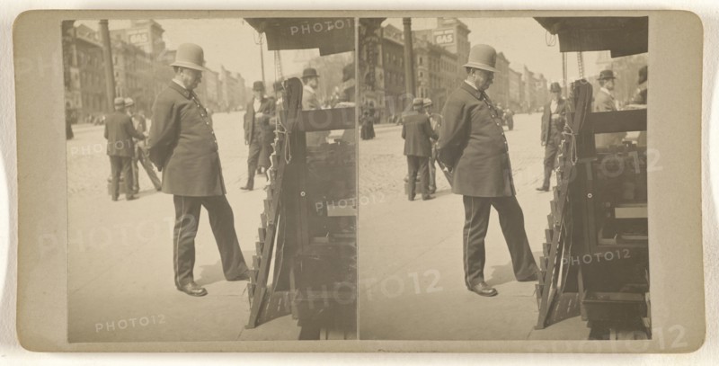 Policeman on Albany, N.Y. street reading newspapers on rack; Julius M. Wendt, American, active 1900s - 1910s, 1900s; Gelatin