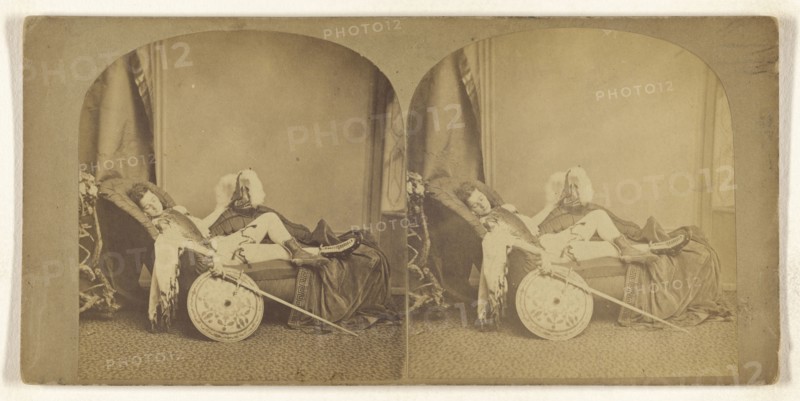 Young soldier asleep on a couch, helmet, sword, and shield in hands; about 1860; Albumen silver print