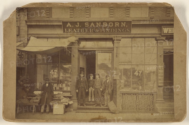 Five men posing in front of establishment of A.J. Sanborn, Leather & Findings; American; about 1875; Albumen silver print