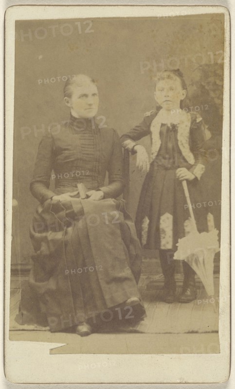 Mother sitting with a book in her lap, girl standing with an umbrella; American; about 1870; Albumen silver print