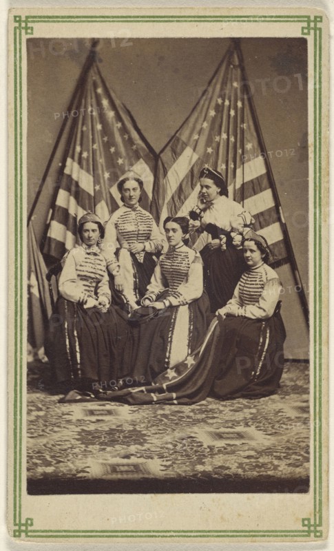Five women, two standing, three seated, in costume, posed in front of two American flags; American; about 1865; Albumen silver