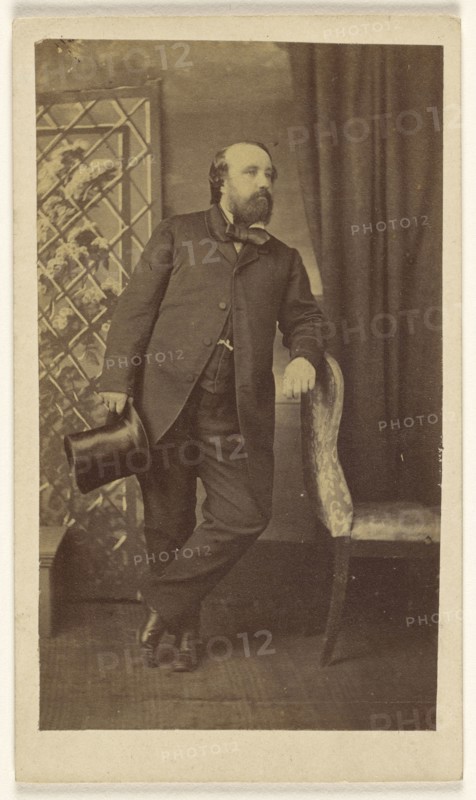Full-bearded man holding a top hat, standing, leaning on chair back; Alexander Anderson, American, 1775 - 1870, 1860s; Albumen