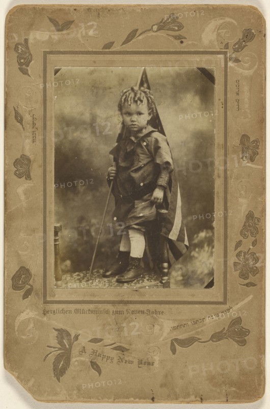 Little boy holding an American flag, standing on a chair; A. Rinin, American, active 1900s, about 1900; Gelatin silver print