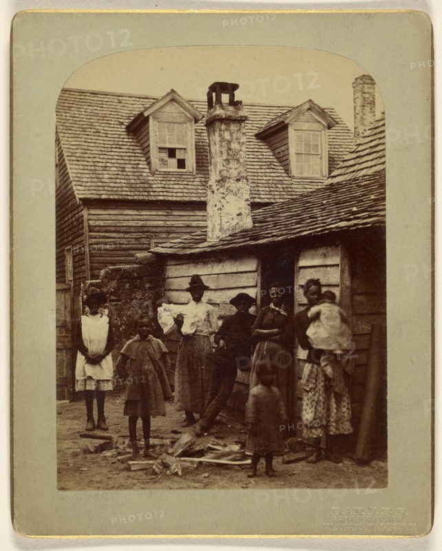 Black family grouping of eight posed at house entrance; George Barker, American, 1844 - 1894, 1886; Albumen silver print