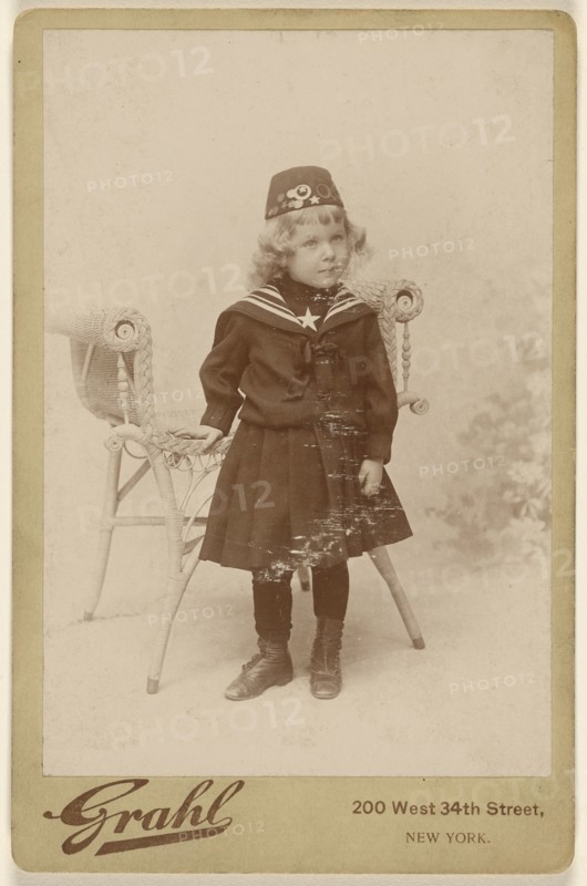 Little girl standing near a chair, wearing a fez; Grahl, American, active New York, New York 1880s - 1890s, about 1890; Gelatin