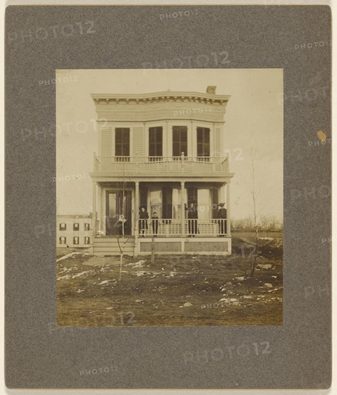 View of a Victorian-style house with five people on the front porch; 1890s; Gelatin silver print