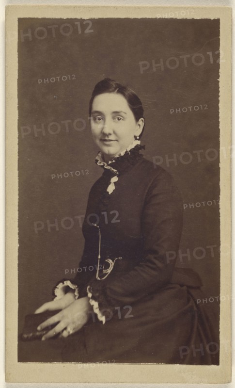 woman wearing a dark dress, holding a book, seated; 1865 - 1870; Albumen silver print