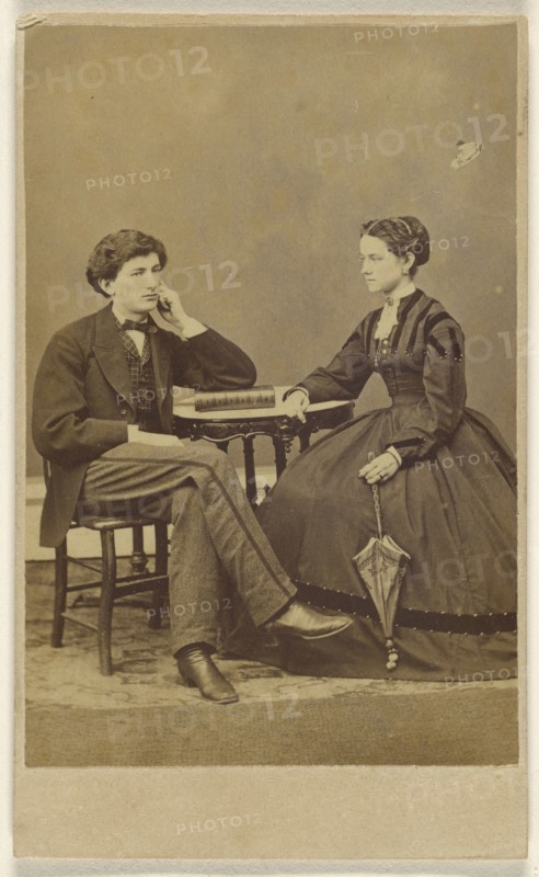 couple seated: man with hand to cheek, elbow on book; woman holding a parasol; S.G. Sheaffer & Company; 1865 - 1870; Albumen