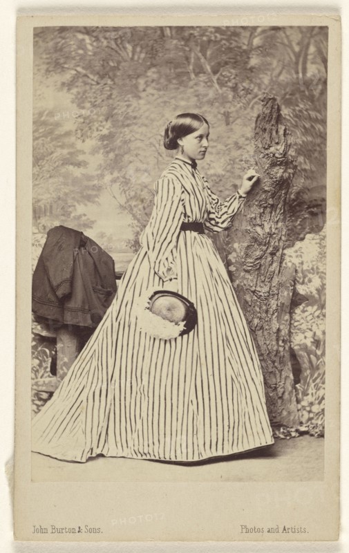woman wearing a striped dress, holding a hat, standing; John Burton & Sons; 1864; Albumen silver print