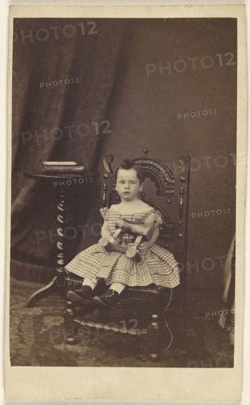 little girl holding a toy wooden horse, seated; 1865 - 1870; Albumen silver print