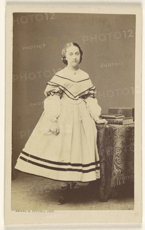 woman standing near a table with books on top; Bayard & Bertall; 1865 - 1875; Albumen silver print