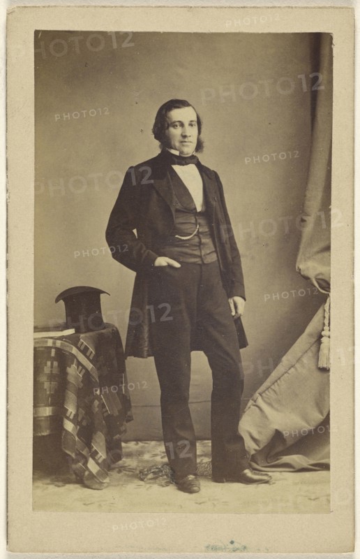 man standing with his hand in his pocket, a top hat on a table nearby; French; 1862; Albumen silver print