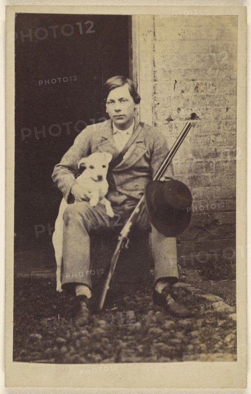Man seated with a white dog, a rifle and hat leaning on his leg; 1865 - 1875; Albumen silver print