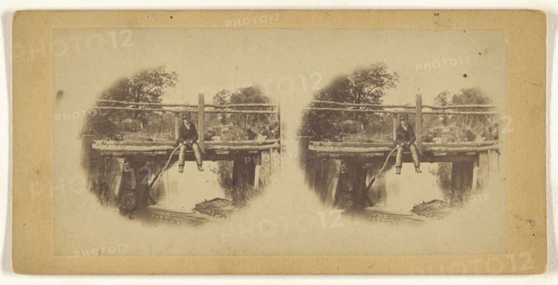 Boy fishing from a bridge, printed in vignette-style; about 1865; Albumen silver print