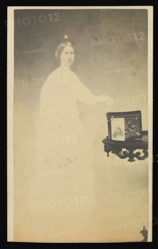 Female  spirit  with a carte-de-visite on a table propped against an album; Attributed to William H. Mumler, American, 1832