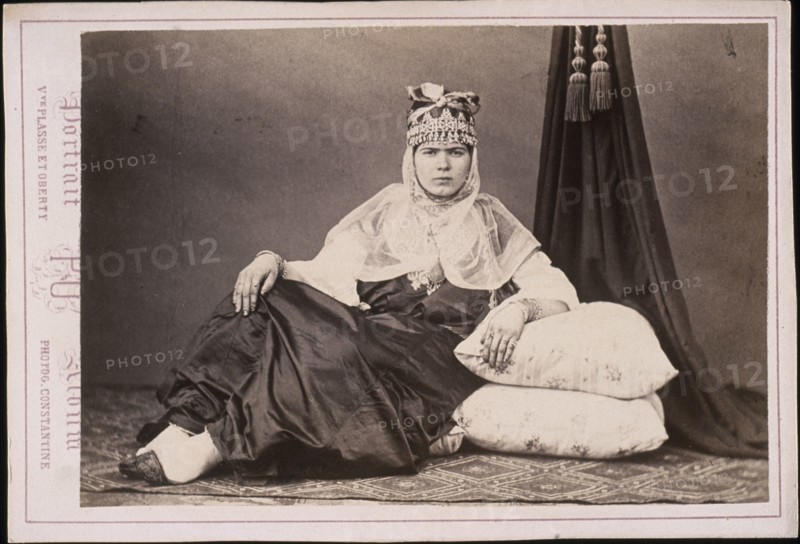 Algerian woman seated on floor with arm resting on cushions, Cities and sites cabinet card collection, Veuve Plasse et Oberty