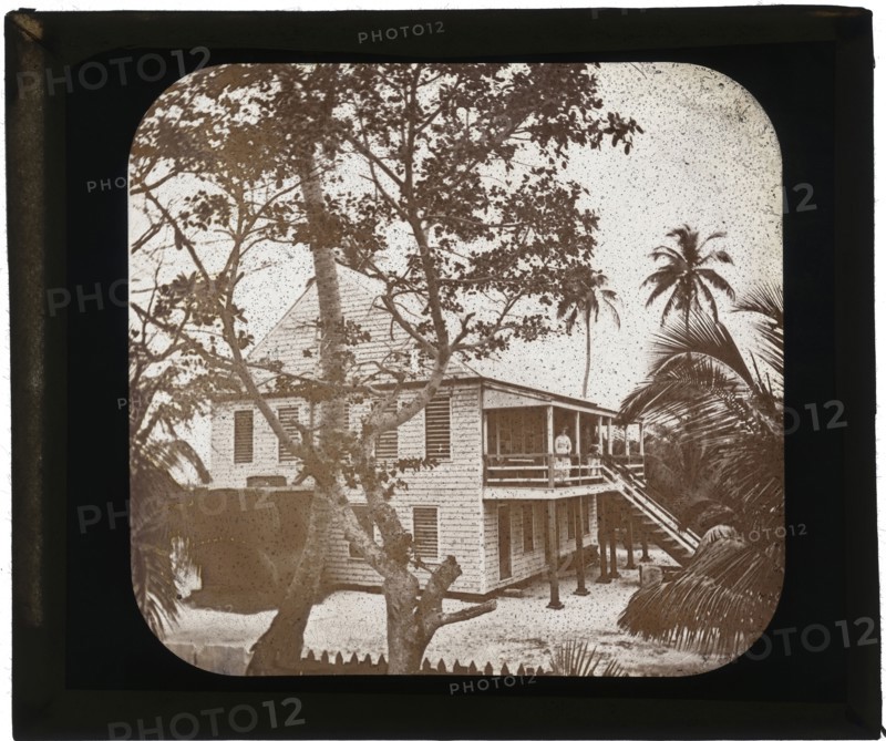 Belize City, ADLP standing on porch of two story white house, Belize City, Augustus and Alice Dixon Le Plongeon papers, 1763