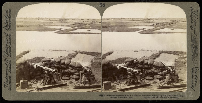 Destructive guns from H.M.S. 'Terrible' and distant burning city fired by their shells, Ricalton, James, Underwood and Underwood