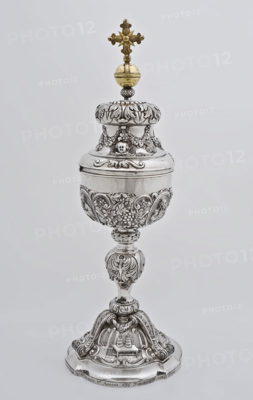 Silver ciborium with lid on which gold-colored cross, ciboric liturgical container holder gold silver, driven chased