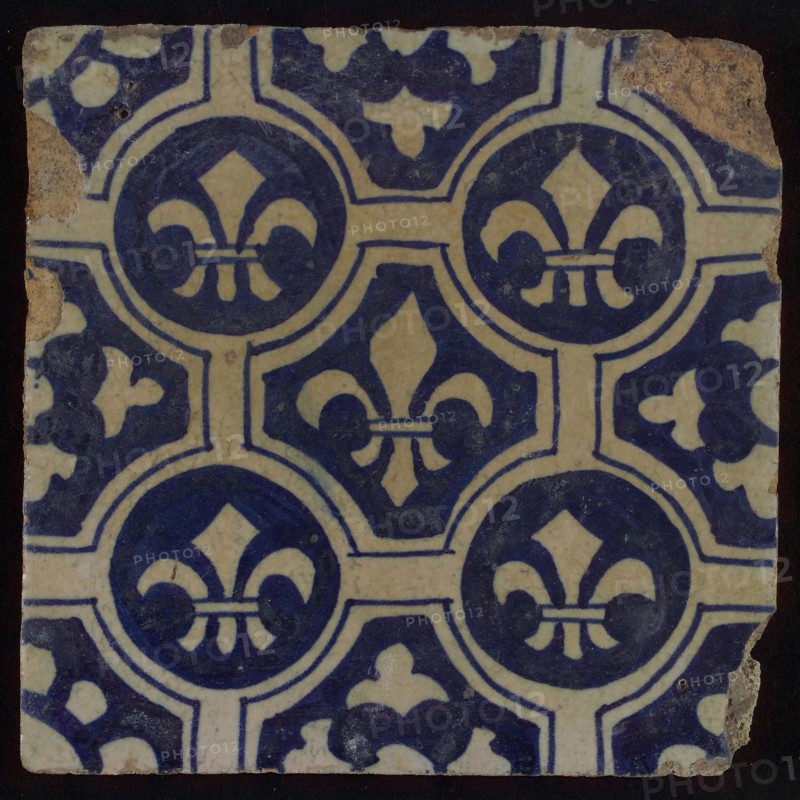 Two-tone tile, blue on white background, four circles with white French lily around central ornament with lily, wall tile